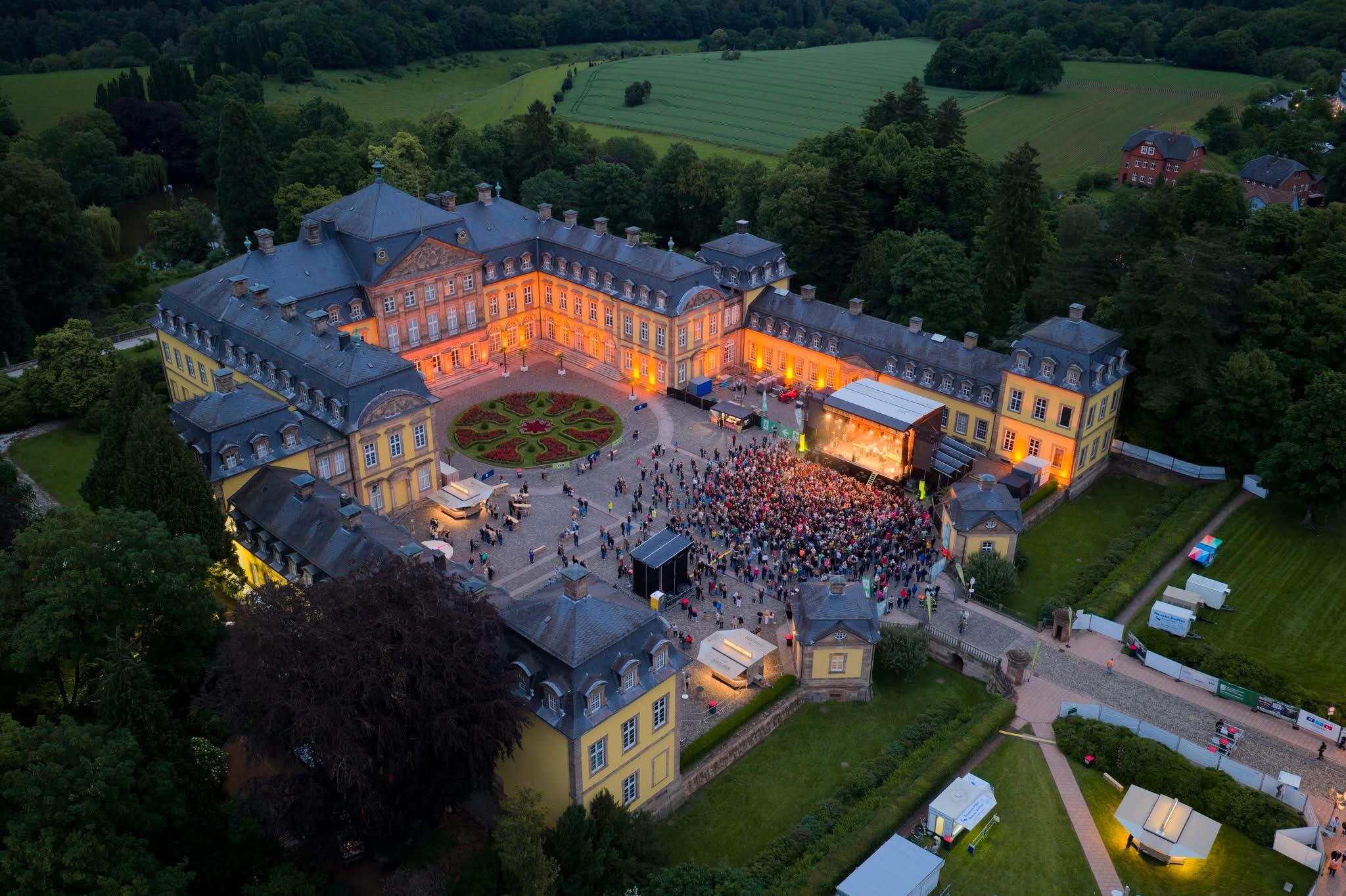 ❤️ DANKE, BAD AROLSEN! ❤️
Wenn wir auf dieses Bild schauen, fällt es schwer zu glauben, dass alles erst vor wenigen Tagen begonnen hat.
Vier Tage lang wurde der Schlosshof des Residenzschlosses Bad Arolsen zu einem Ort voller Musik, Begegnungen und unvergesslicher Momente. Rund 7.500 Besucherinnen und Besucher haben gemeinsam mit uns die Premiere des ersten Bad Arolsen Schlosshof Open Air gefeiert.
Dick Brave & Band eröffneten das Wochenende mit jeder Menge Rock’n’Roll, LaBrassBanda verwandelten den Schlosshof in eine riesige Party, Álvaro Soler brachte mediterranes Sommerfeeling nach Nordhessen und Karat sorgten mit ihren zeitlosen Klassikern für einen stimmungsvollen und würdigen Abschluss.
Was uns besonders berührt hat, war die Begeisterung des Publikums. Menschen aus Bad Arolsen, der Region und weit darüber hinaus haben gezeigt, dass Live-Musik hier zuhause ist und dass dieser besondere Ort eine Zukunft als Konzertspielstätte hat.
Deshalb können wir heute schon sagen:
🏰 Wir kommen wieder!
Das Bad Arolsen Schlosshof Open Air war keine einmalige Veranstaltung. Wir freuen uns schon jetzt darauf, gemeinsam mit Ihnen und Euch die Geschichte dieses besonderen Open-Air-Festivals weiterzuschreiben.
Unser besonderer Dank geht an unsere Medienpartner & Sponsoren:
▶️WLZ / Waldeckische Landeszeitung
▶️HIT RADIO FFH
▶️RTL Hessen
▶️Sparkasse Waldeck-Frankenberg
▶️Fürstliches Hofbrauhaus Arolsen
▶️Welcome Hotel Bad Arolsen - Natürlich
▶️Hotel Brunnenhaus Schloss Landau
...und natürlich auch:
▶️Fürst Waldeck mit Silvia Mertin und Team
▶️ DRK Bad Arolsen
▶️ Stadtverwaltung & Ordnungsamt Bad Arolsen
▶️Feuerwehr Bad Arolsen
▶️RL Security RL
▶️Foodsoul Catering
▶️ Stagepoint
▶️ Emmert Veranstaltungstechnik
▶️PS Sound
▶️Publikumscatering (der Hausmetzger Thorsten Leimbach, u.v.a.)
Und natürlich an Sie und Euch – unser Publikum.
Ohne Euch wäre dieses Bild nicht möglich gewesen. ❤️
Bis bald im Schlosshof!
Ihre und Eure
Bad Arolsen Schlosshof Open Air Crew
(📸 Drohnenfoto: Dana Gärtner)